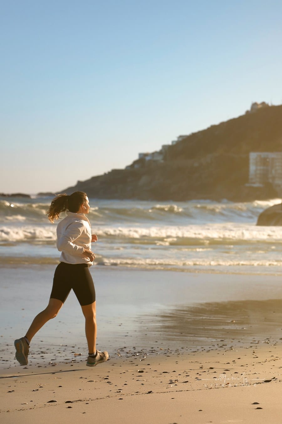 Side portrait of woman running by the beach