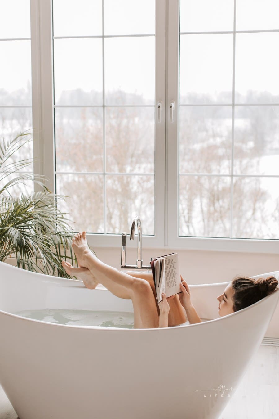 woman relaxing in bath while reading a book