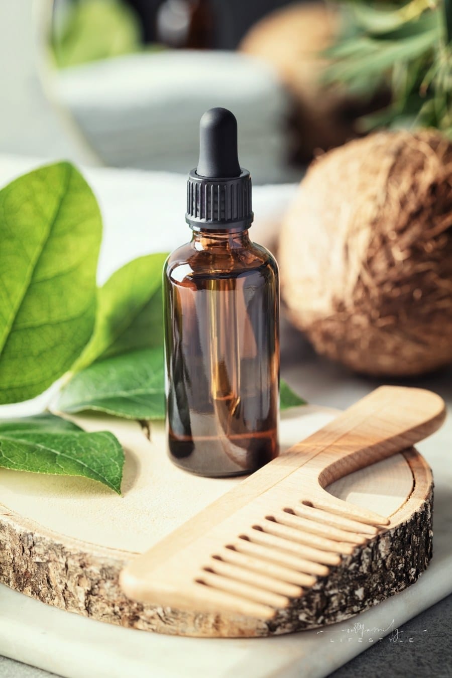 natural organic coconut oil in amber glass bottle and wooden hair brush