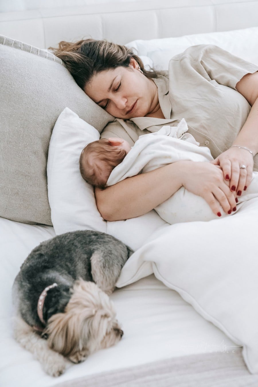 Young mom with cute baby and dog sleeping on bed