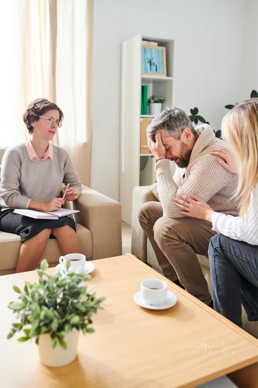 Frustrated man crying while wife supporting him at therapy session