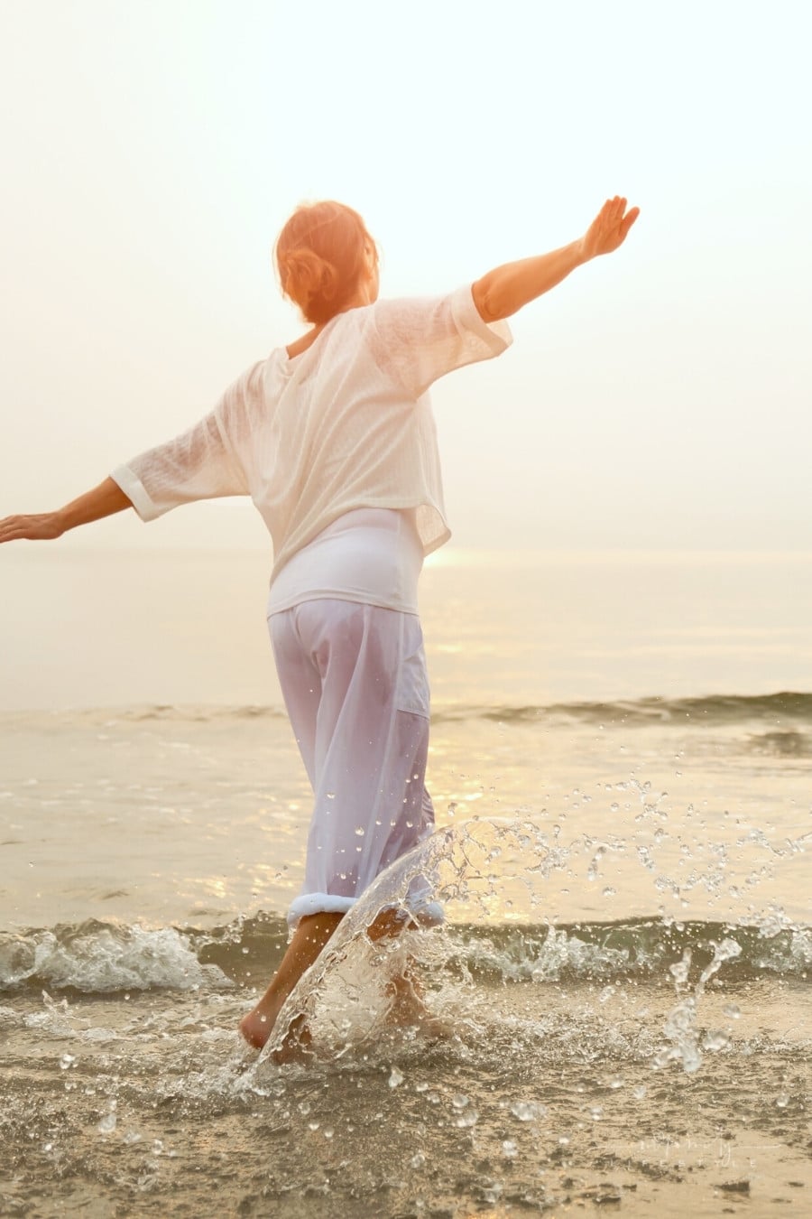carefree woman dancing in the sun on the beach