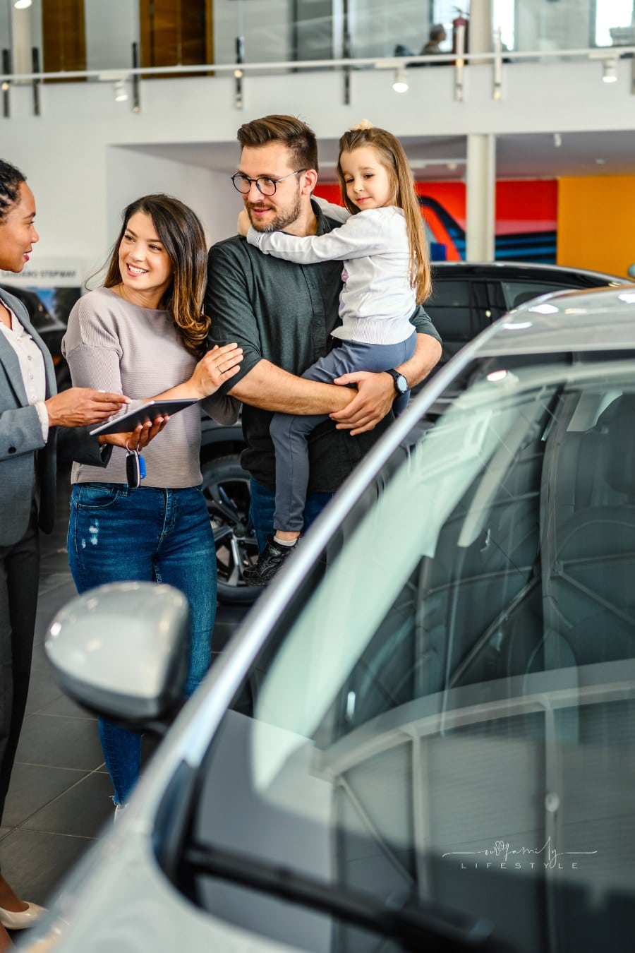 Saleswoman at car dealership center helping family to choose new family vehicle