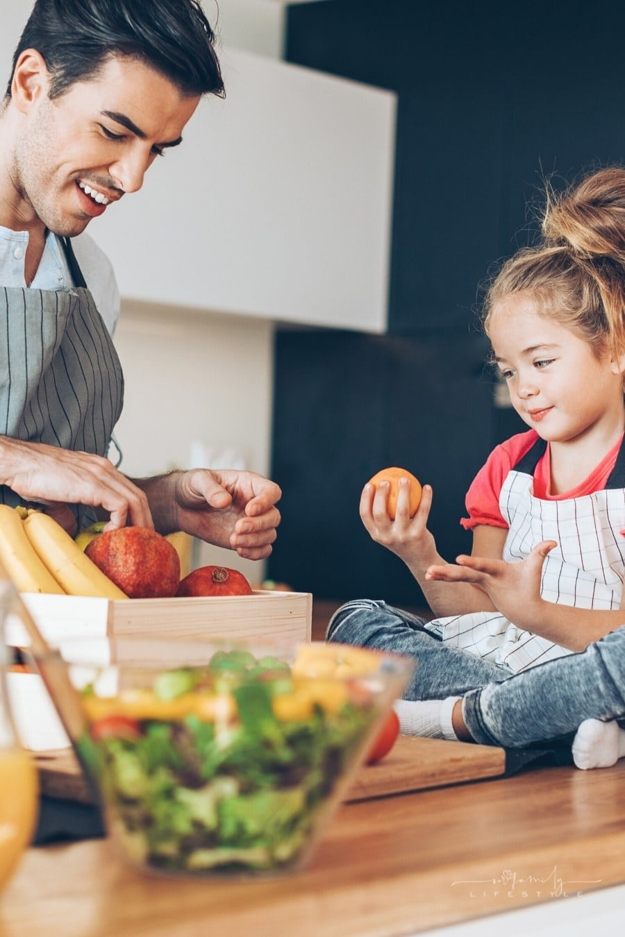 father and daughter looking at fruits in kitchen