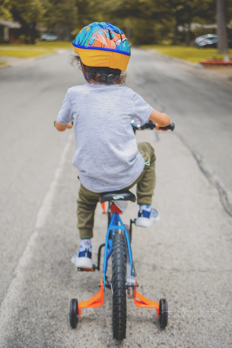 A Kid Riding a Bike while wearing a helmet