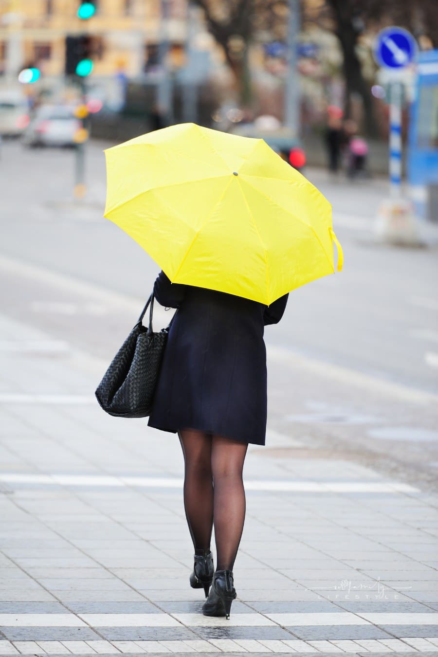 Pedestrian with yellow umbrella on sidewalk