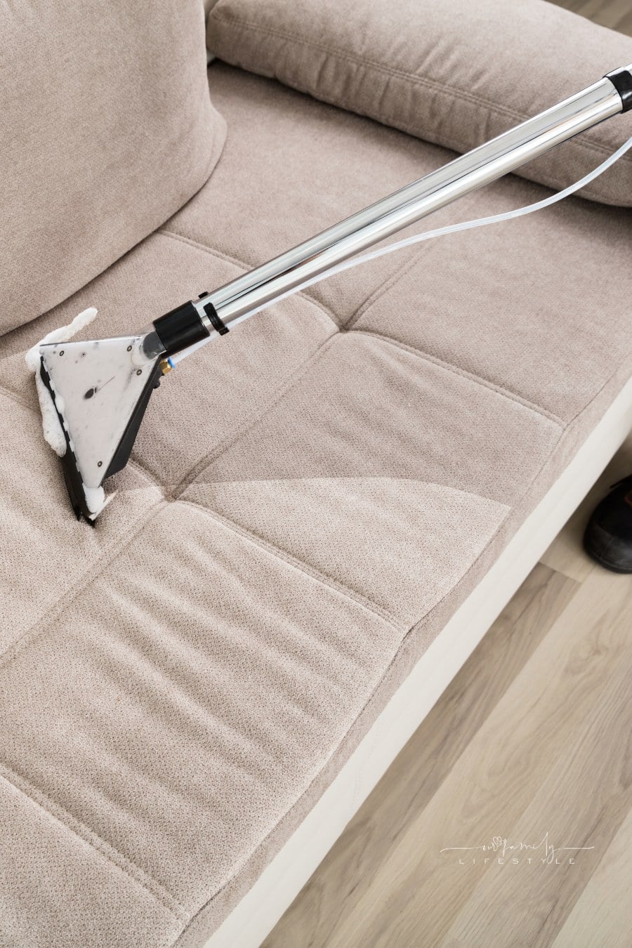 Person Cleaning Sofa With Vacuum Cleaner