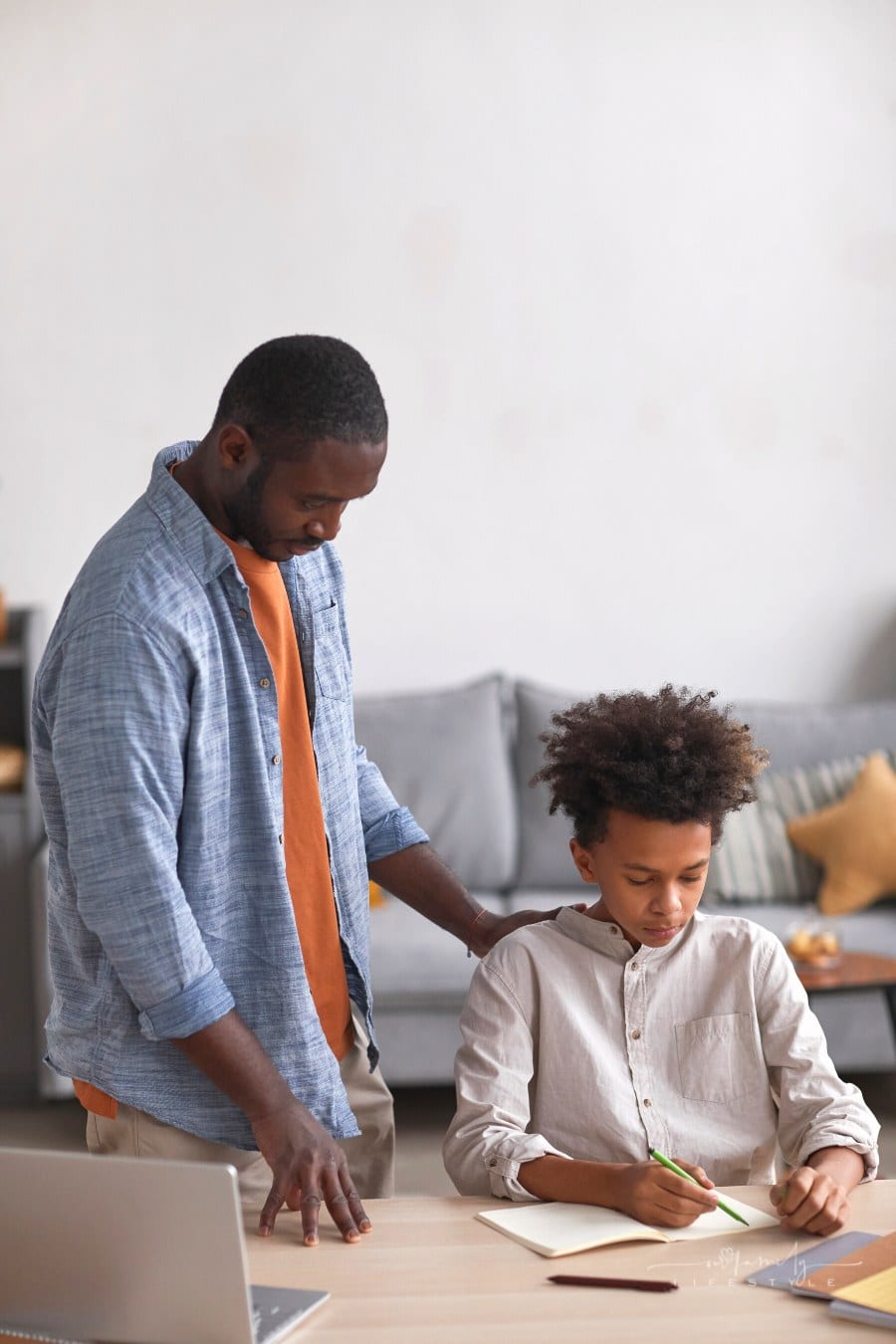 caring father helping teenage son do homework