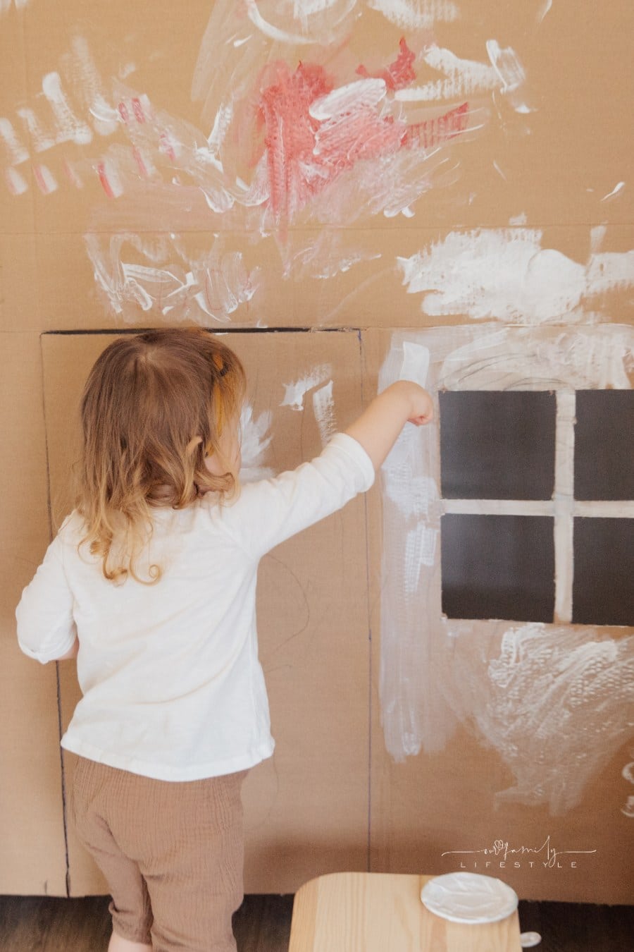 Child Painting Cardboard box to look like a house
