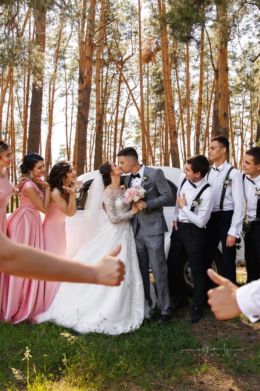 Happy wedding. Bridesmaids and groomsmen having fun while bride and groom kiss