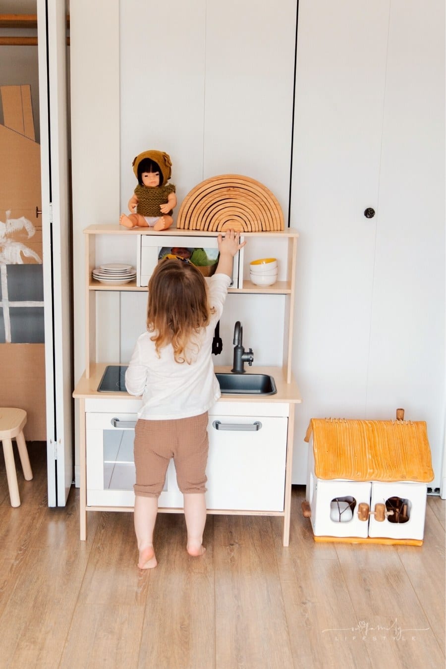 toddler playing with wooden play kitchen