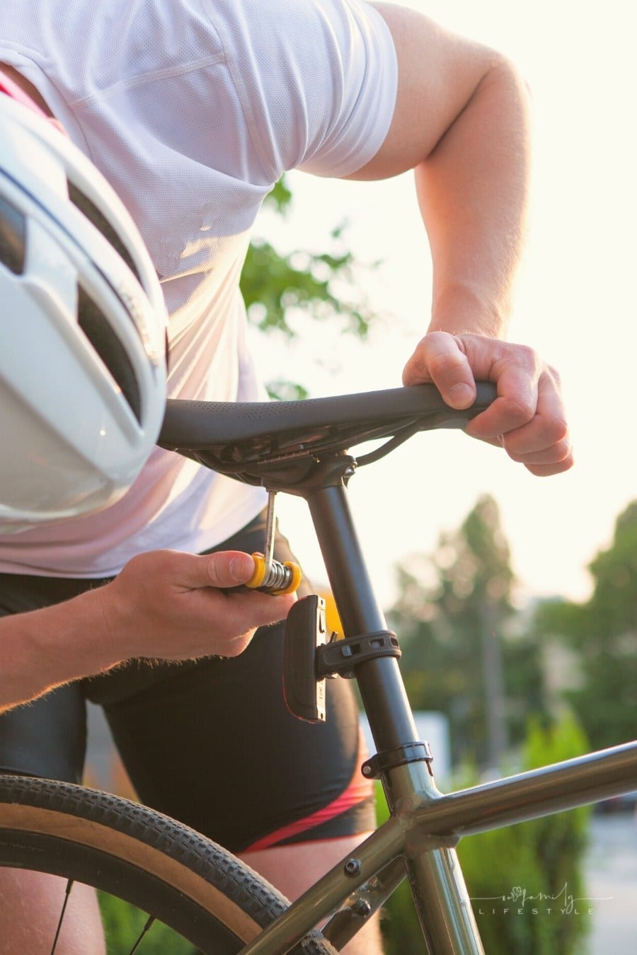 cyclist in bike helmet fixing bicycle seat