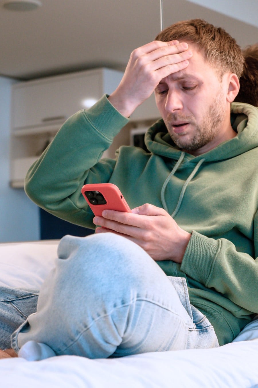 Worried and anxious man clutching head while holding a phone