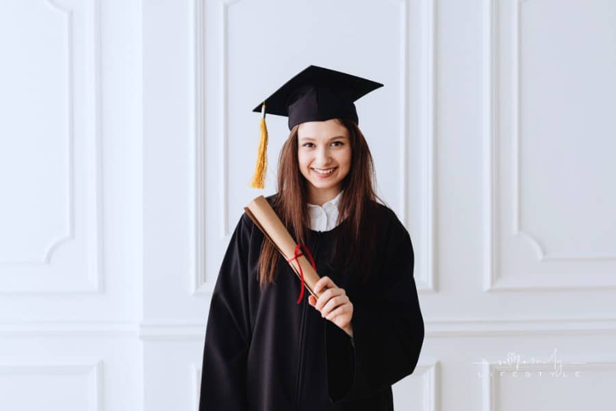 female graduate in cap and gown holding a scroll diploma