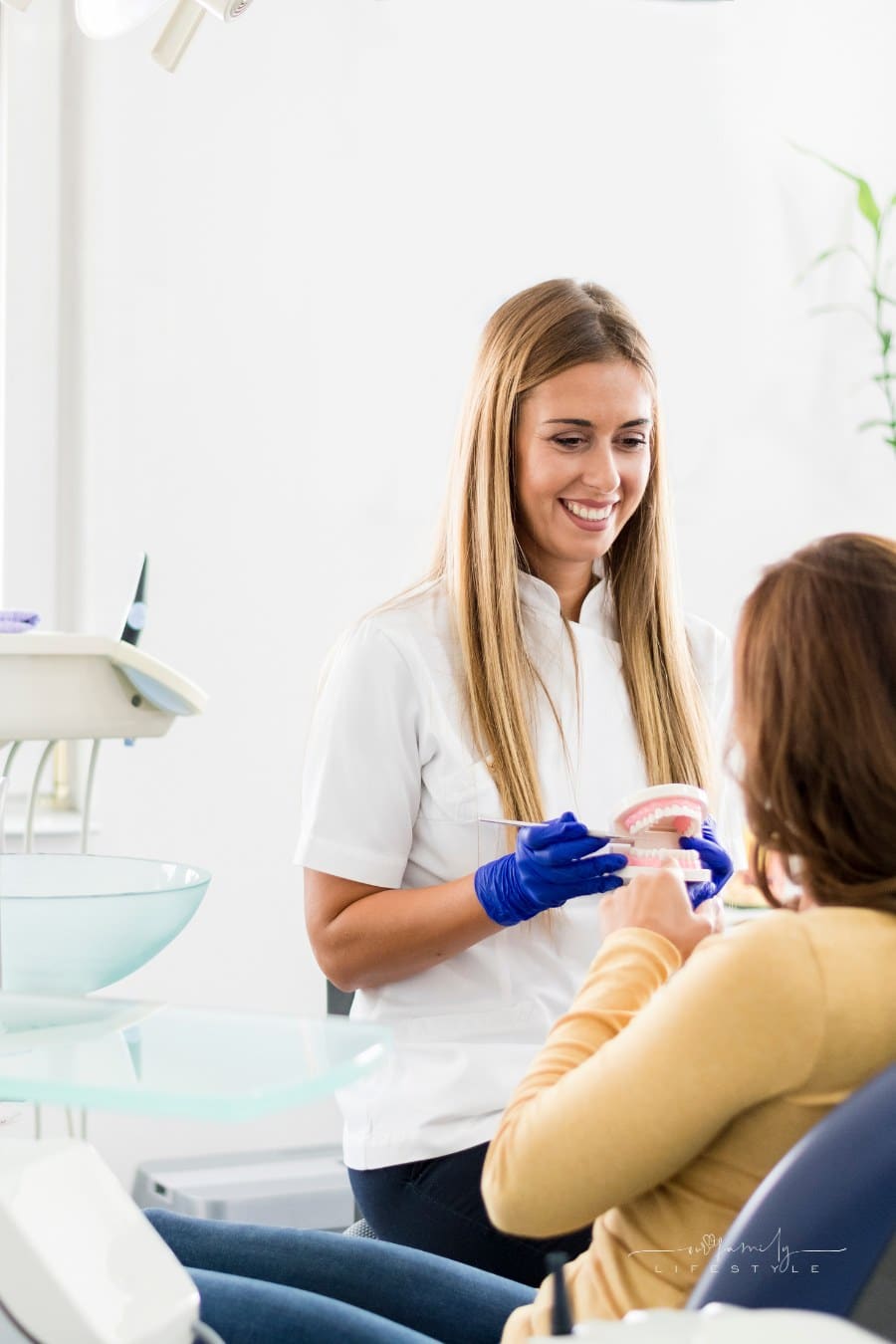 Dentist at office teaching young woman to how to take care of teeth
