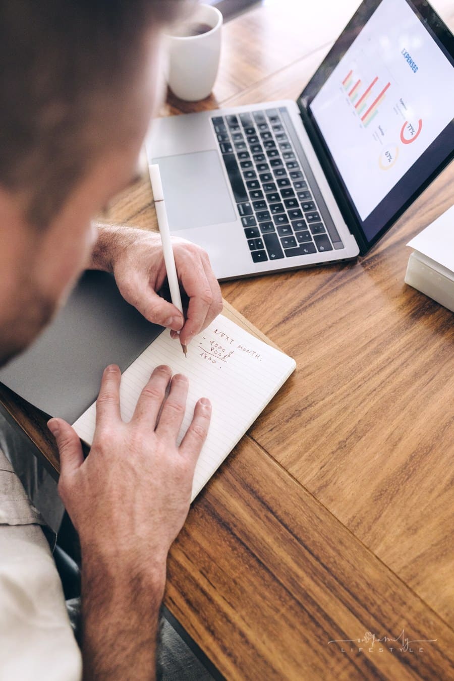 couple looking at finance charts on laptop while writing family budget