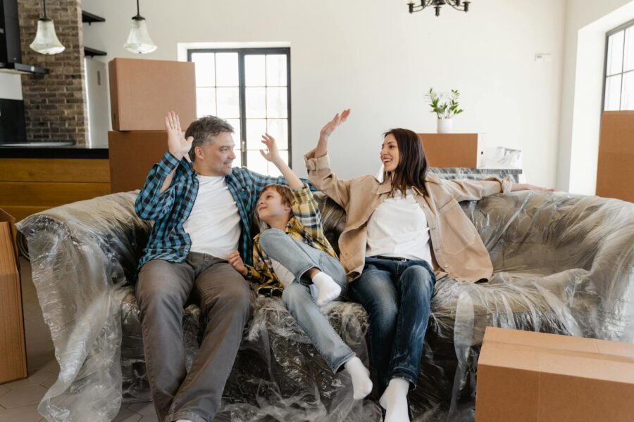A cheerful family sitting on a couch amidst moving boxes, celebrating their new home.