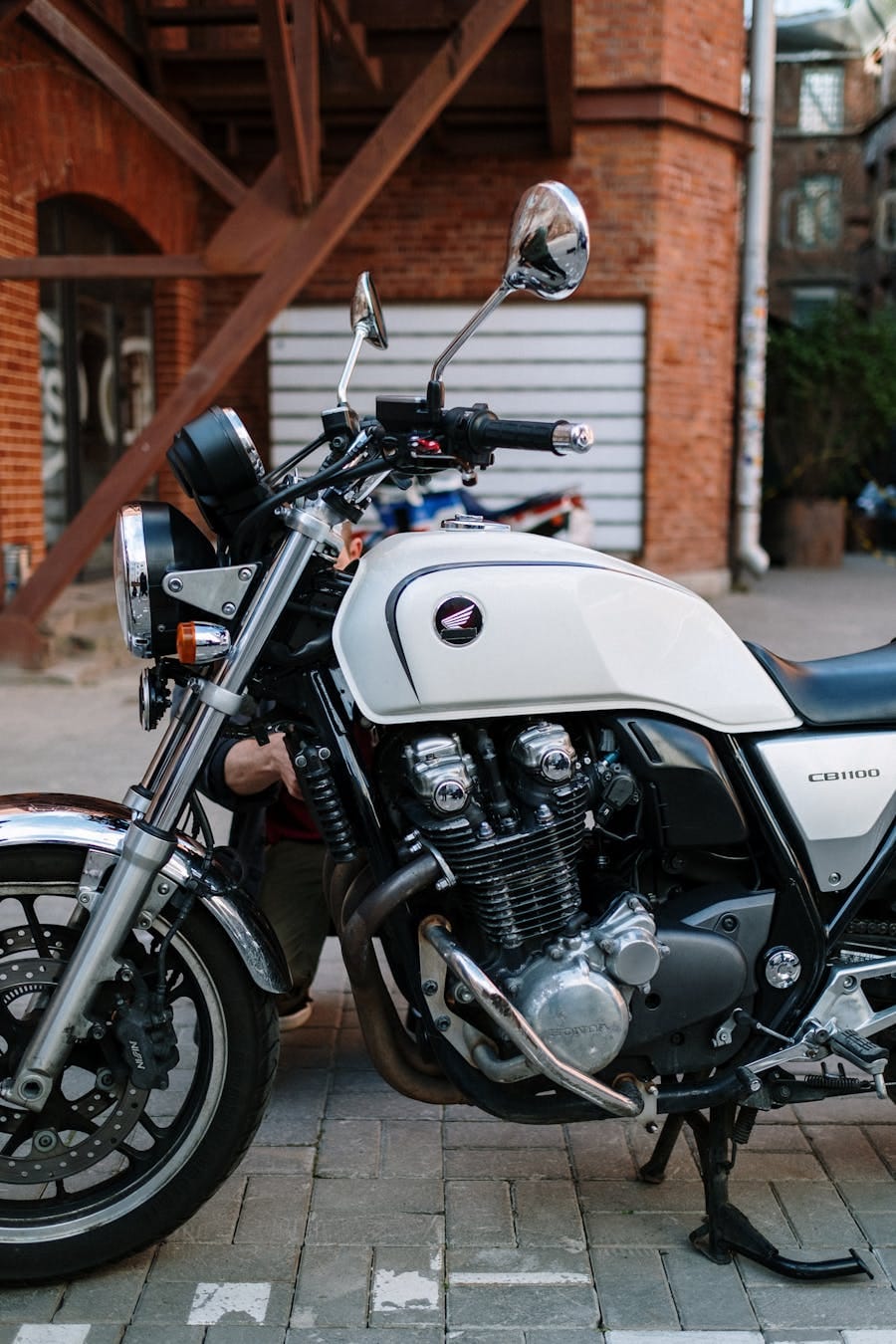 A classic motorcycle parked on a street by a brick building, showcasing its chrome and vintage design.