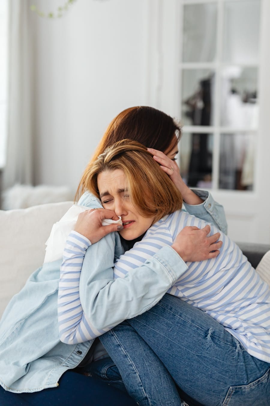 A comforting hug between two women showing support and compassion indoors.