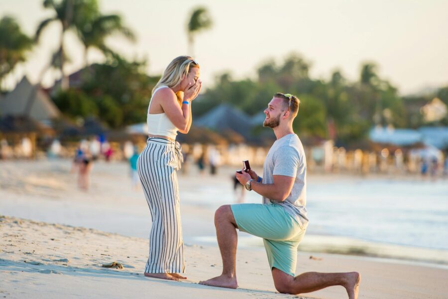 A couple shares a loving moment during a beach proposal in Antigua at sunset.