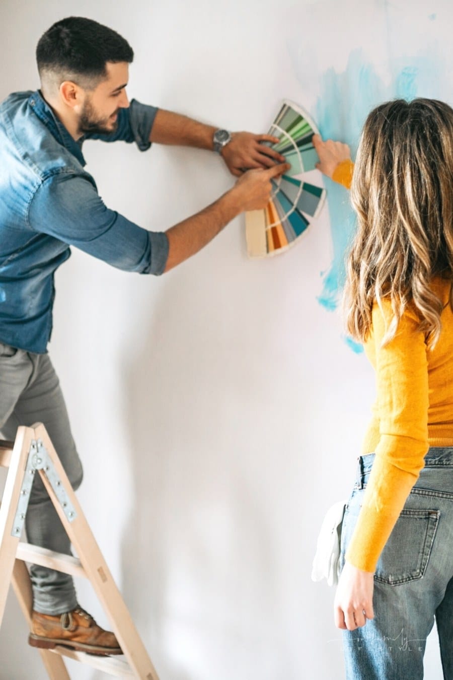 couple using a color wheel against a wall to choose paint