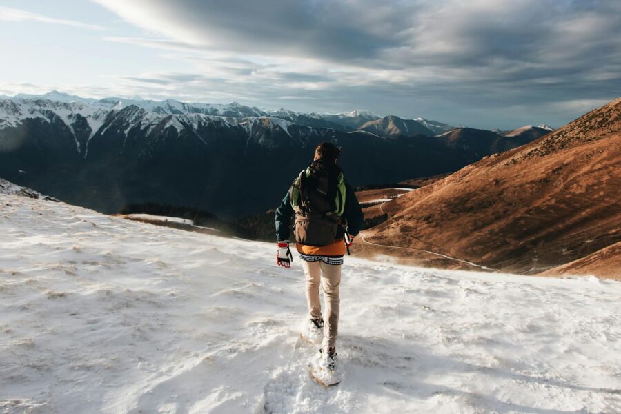 A hiker walking on snowy terrain with breathtaking mountain views on a winter day.