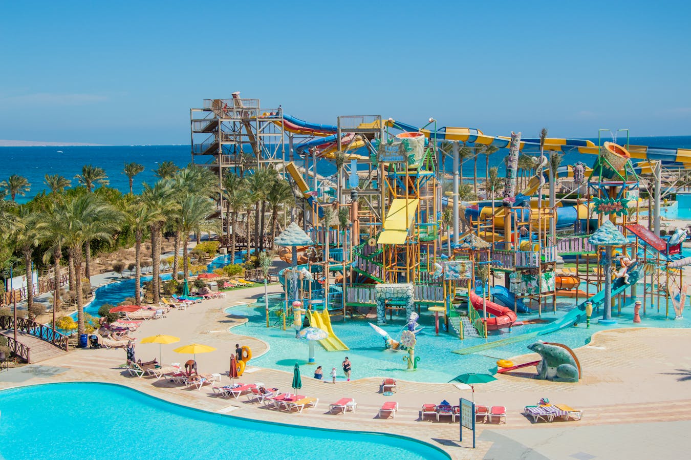 A lively outdoor water park featuring colorful slides and pools by the seaside.