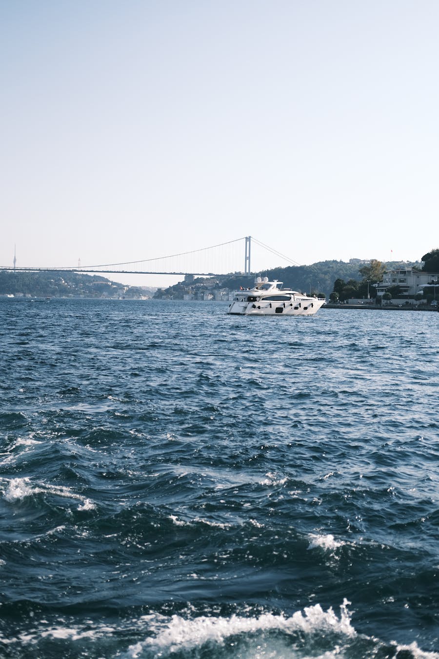 A luxury yacht sailing on the Bosporus with the iconic bridge in the background in Istanbul, Turkey.