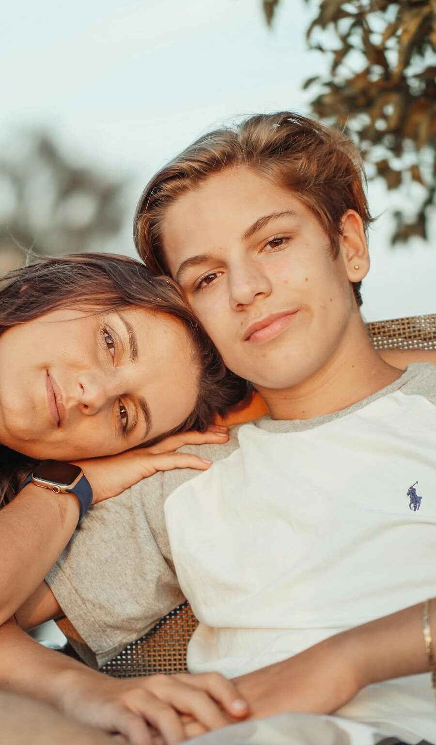 A mother and teenage son sitting together outdoors, enjoying a peaceful moment.