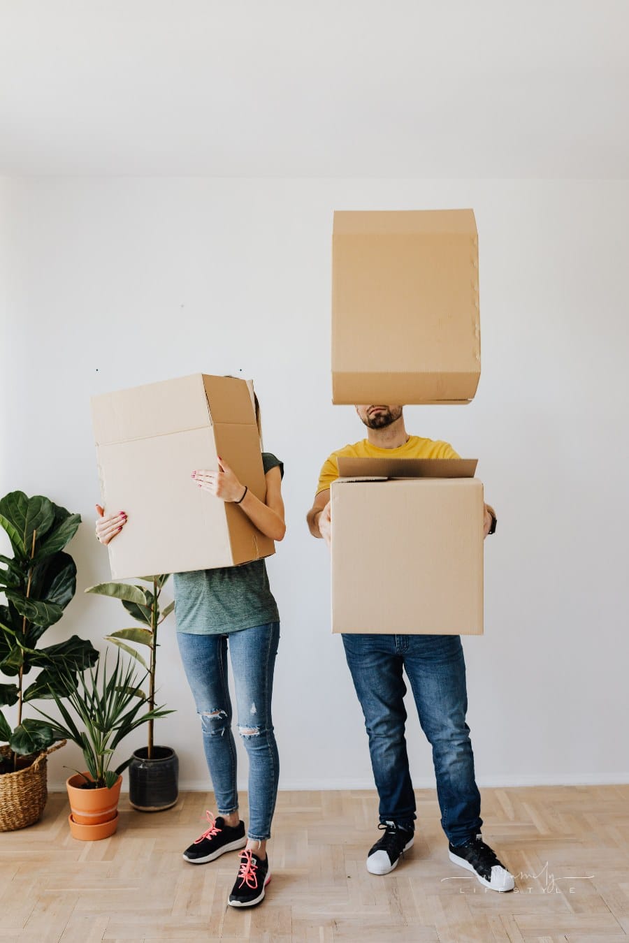 man and woman carrying moving boxes