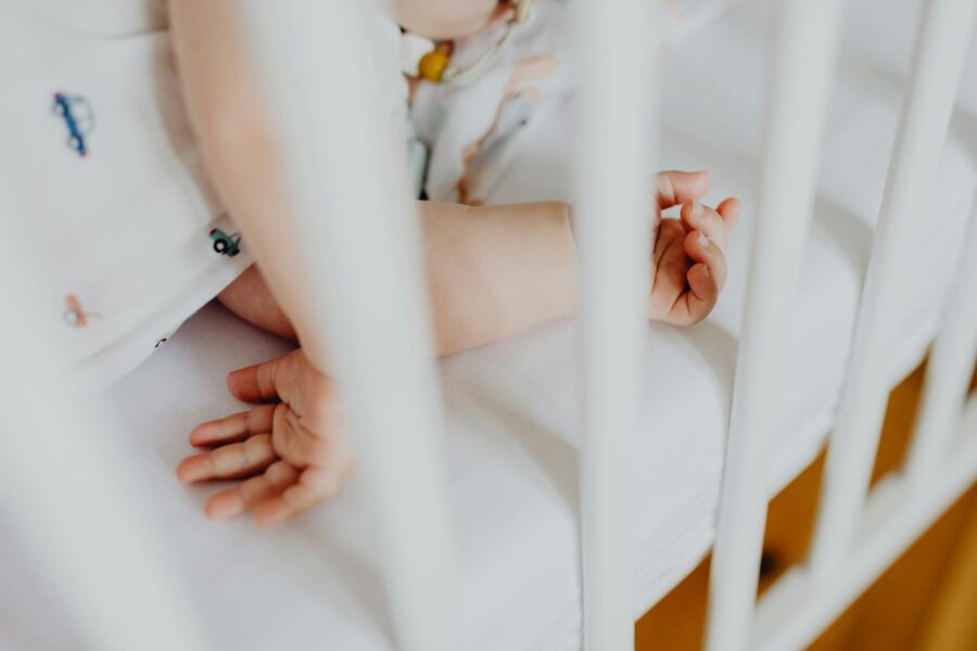 A serene image of a baby sleeping in a crib, showcasing adorable small hands and arms.