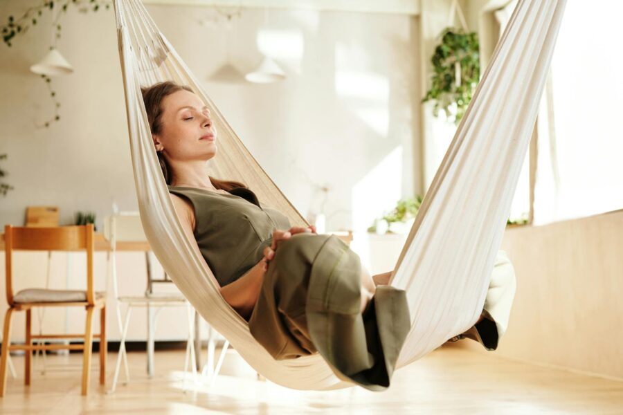 A woman enjoys a peaceful nap on an indoor hammock under soft natural light.