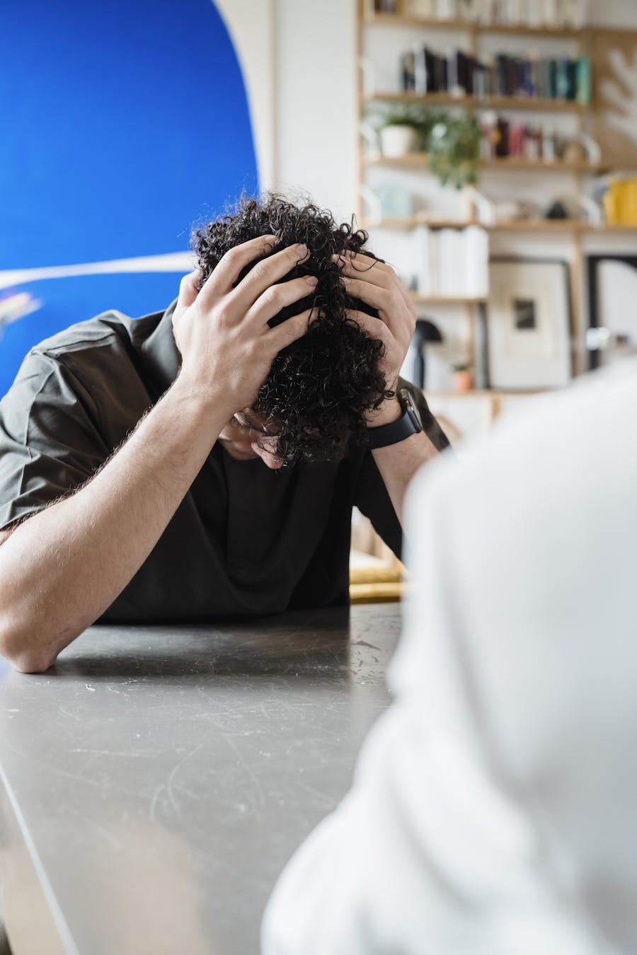A young man experiencing emotional distress during a counseling session, indoors.