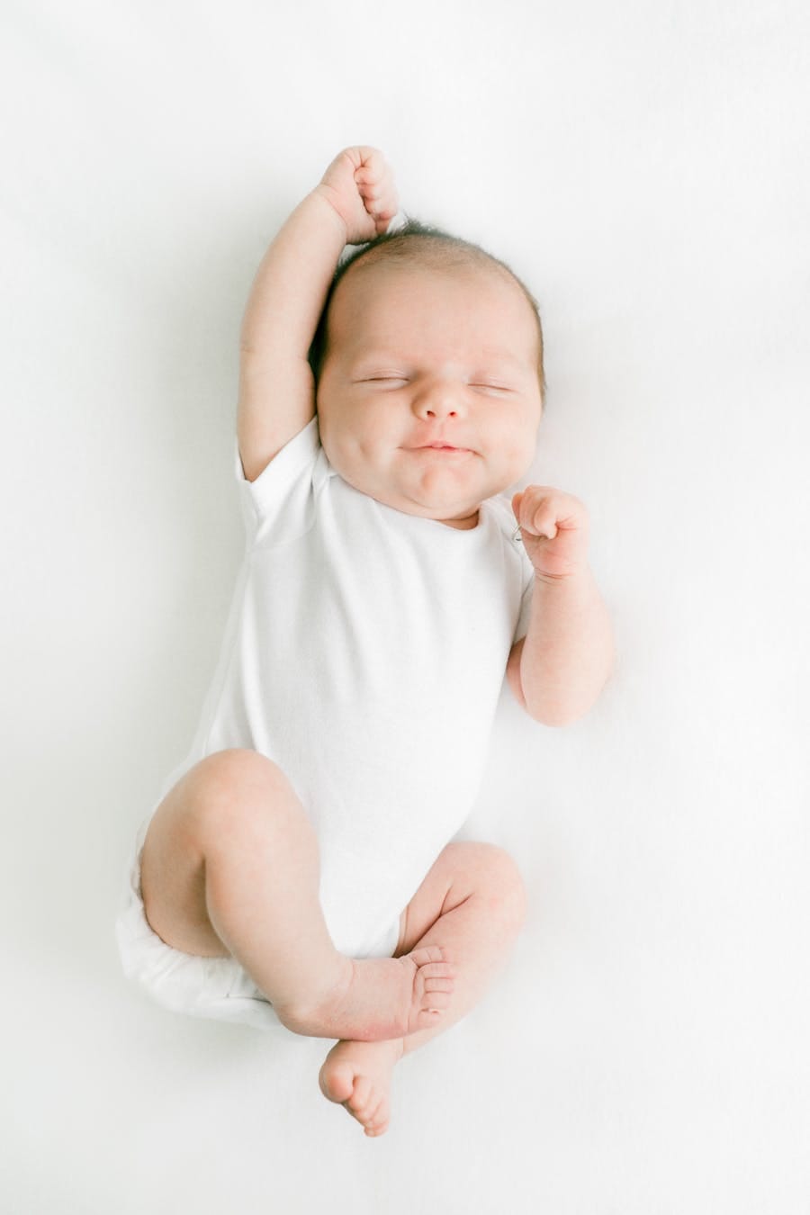 Adorable baby peacefully sleeping on a white background in a relaxed pose.