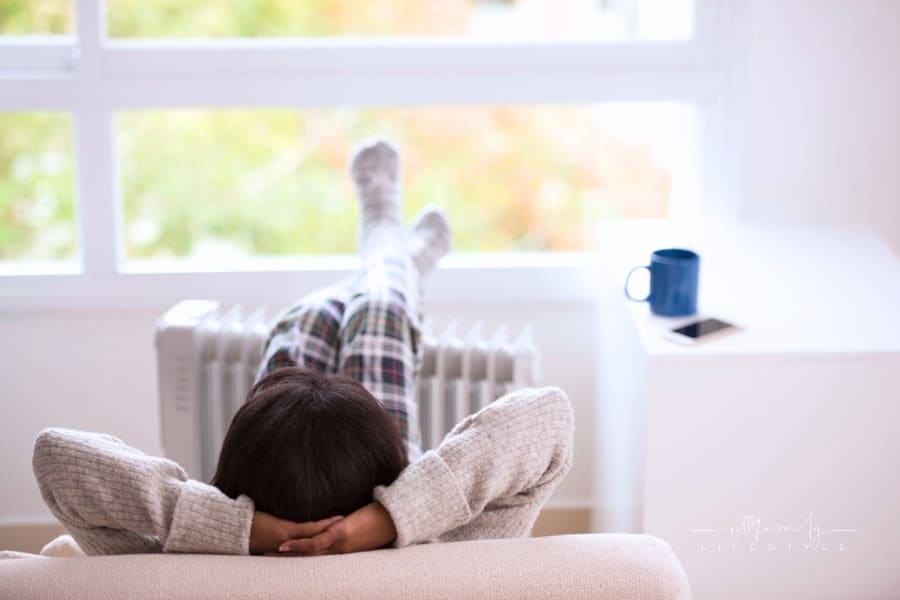 Cozy woman warming up with feet n socks on radiator