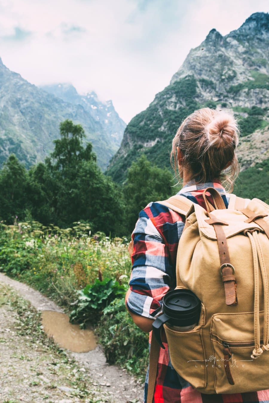 woman hiker with backpack looking at alpine view of mountains
