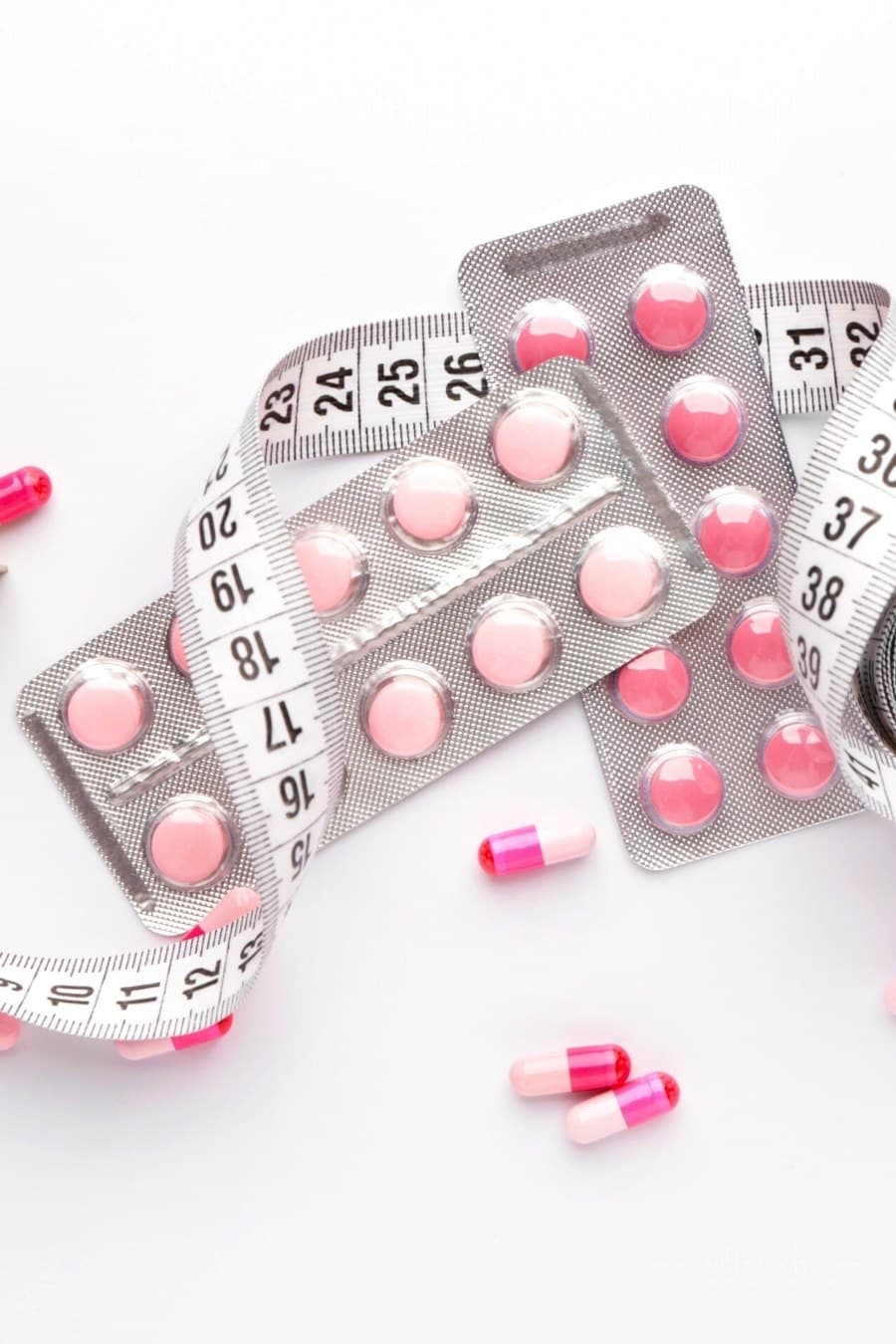 weight loss pills wrapped in white measuring tape