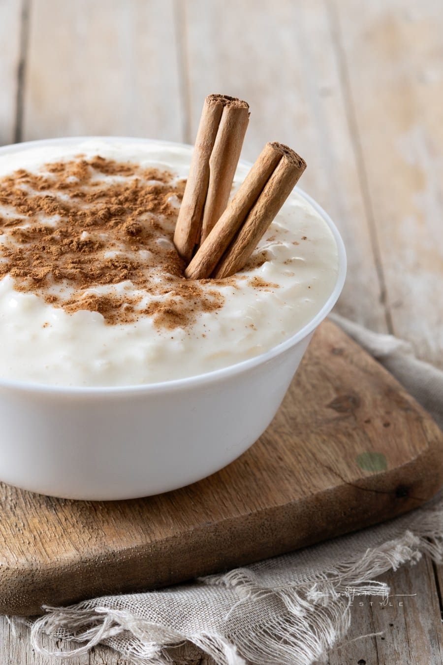 Arroz con leche. Rice pudding with cinnamon in bowl on wooden cutting board