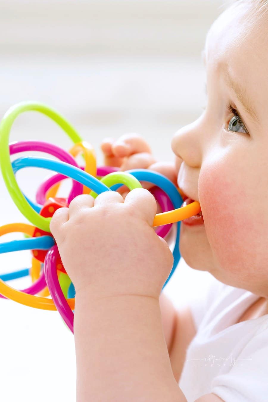 Baby chewing on bright teether toy