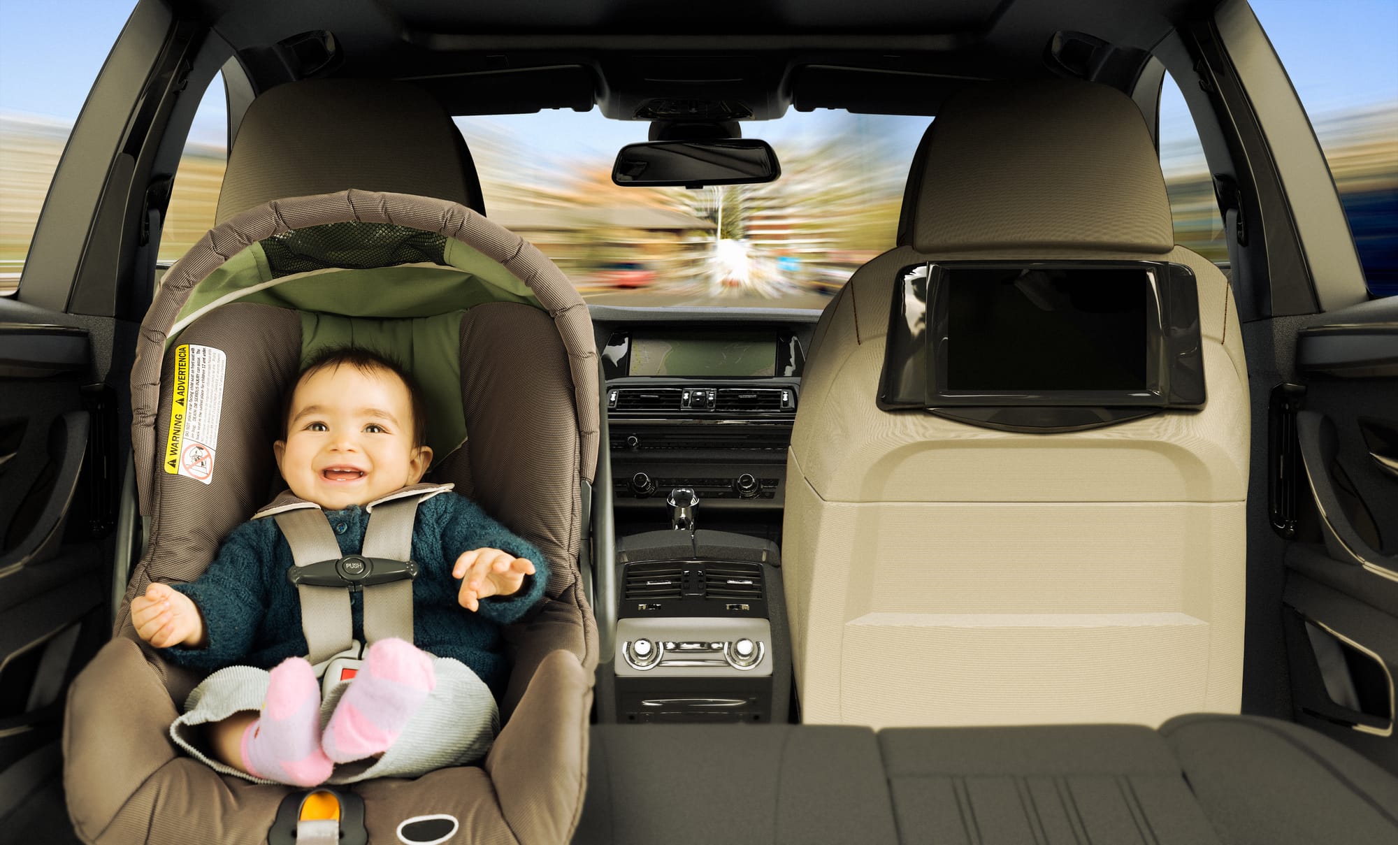 A baby girl in the back seat of a car in a child safety seat