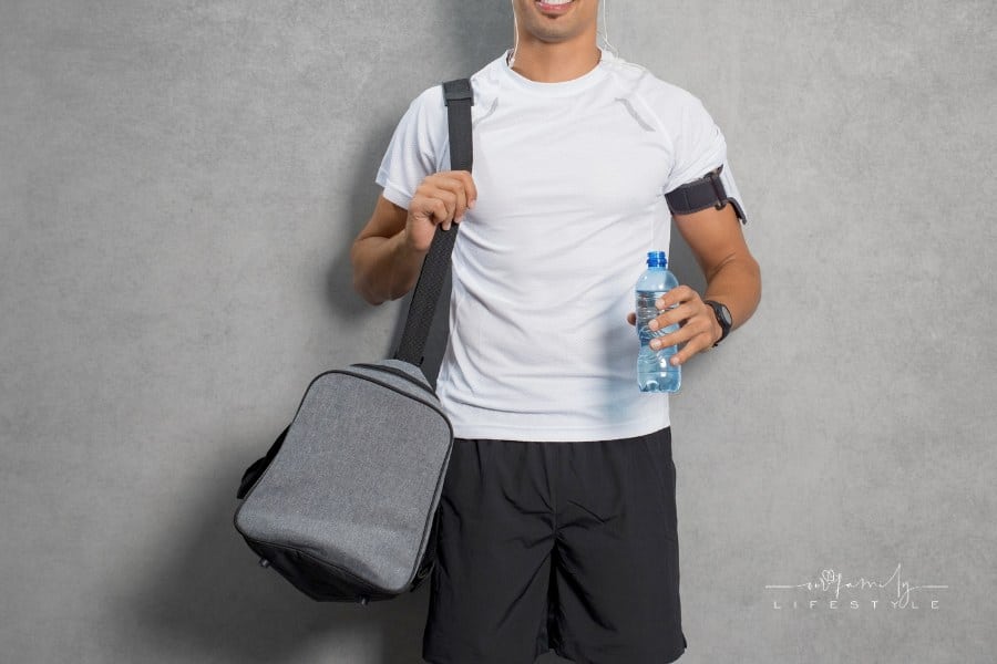 young man with a gym bag over his shoulder and a bottle of water in other hand