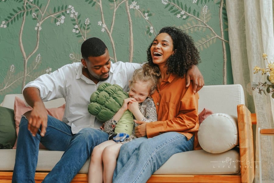 A Happy Couple Sitting on a Couch with their Daughter