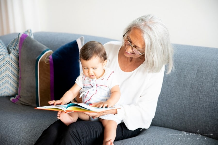 elderly woman reading book to toddler on her lap