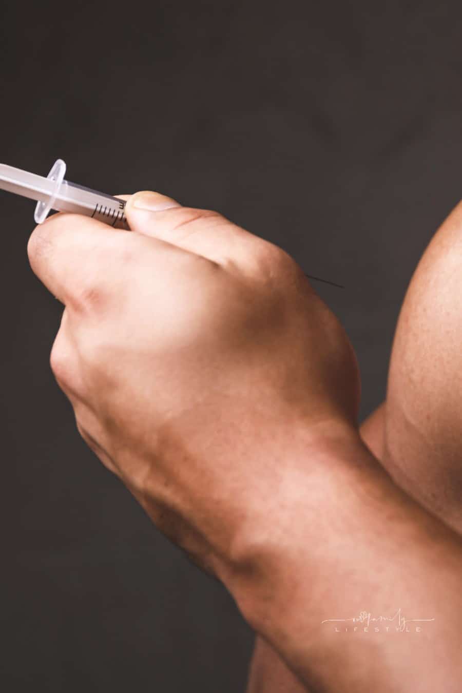 Muscular man with a syringe for Testosterone Replacement Therapy in his hand