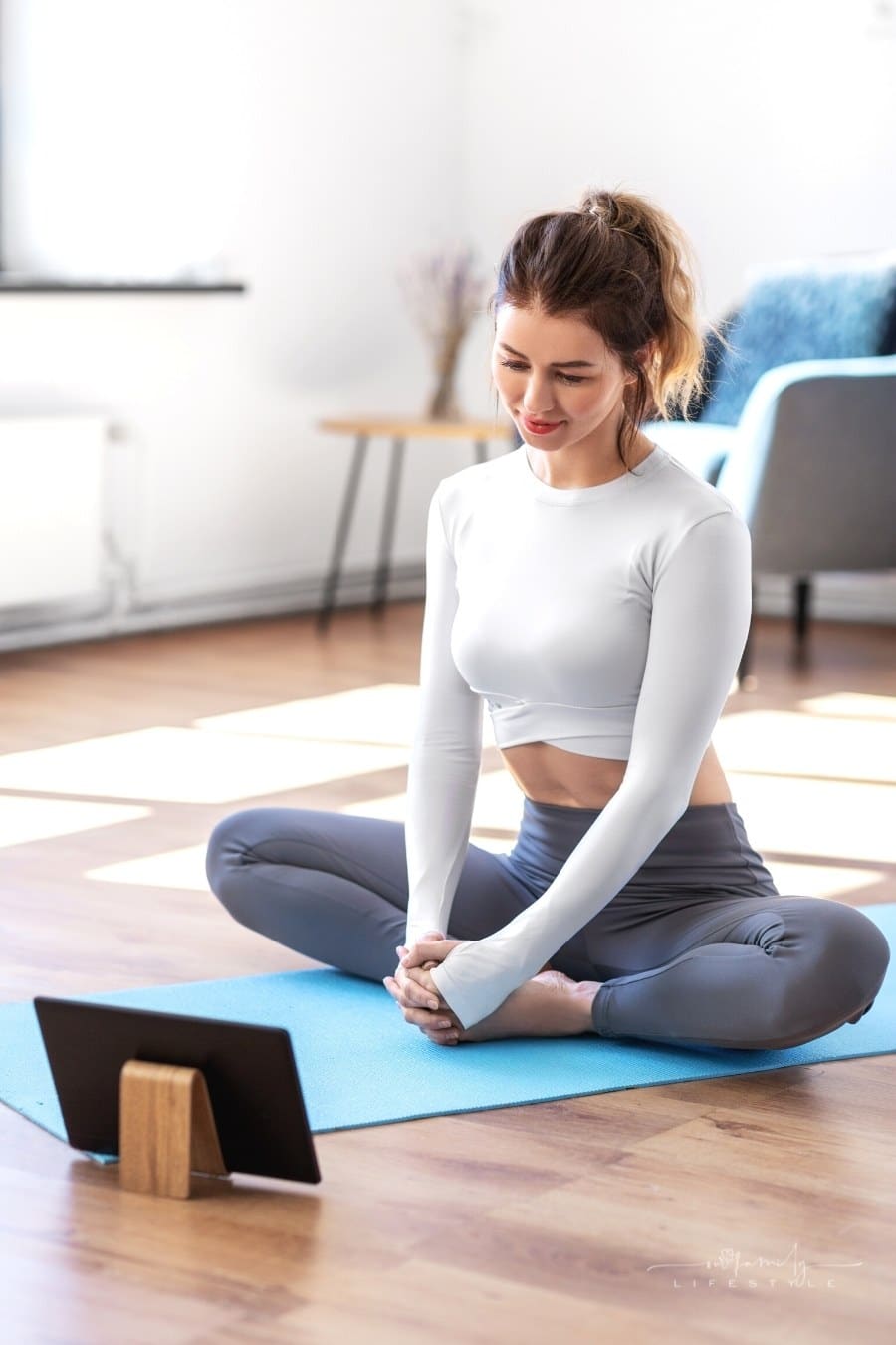 young woman watching youtube fitness videos on yoga mat