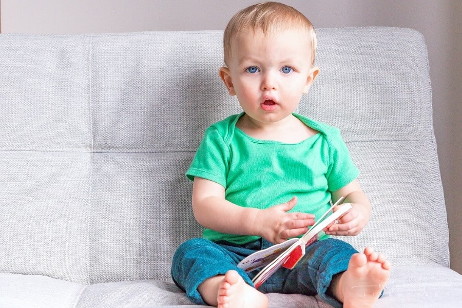 baby holding a board book and looking directly at the camera