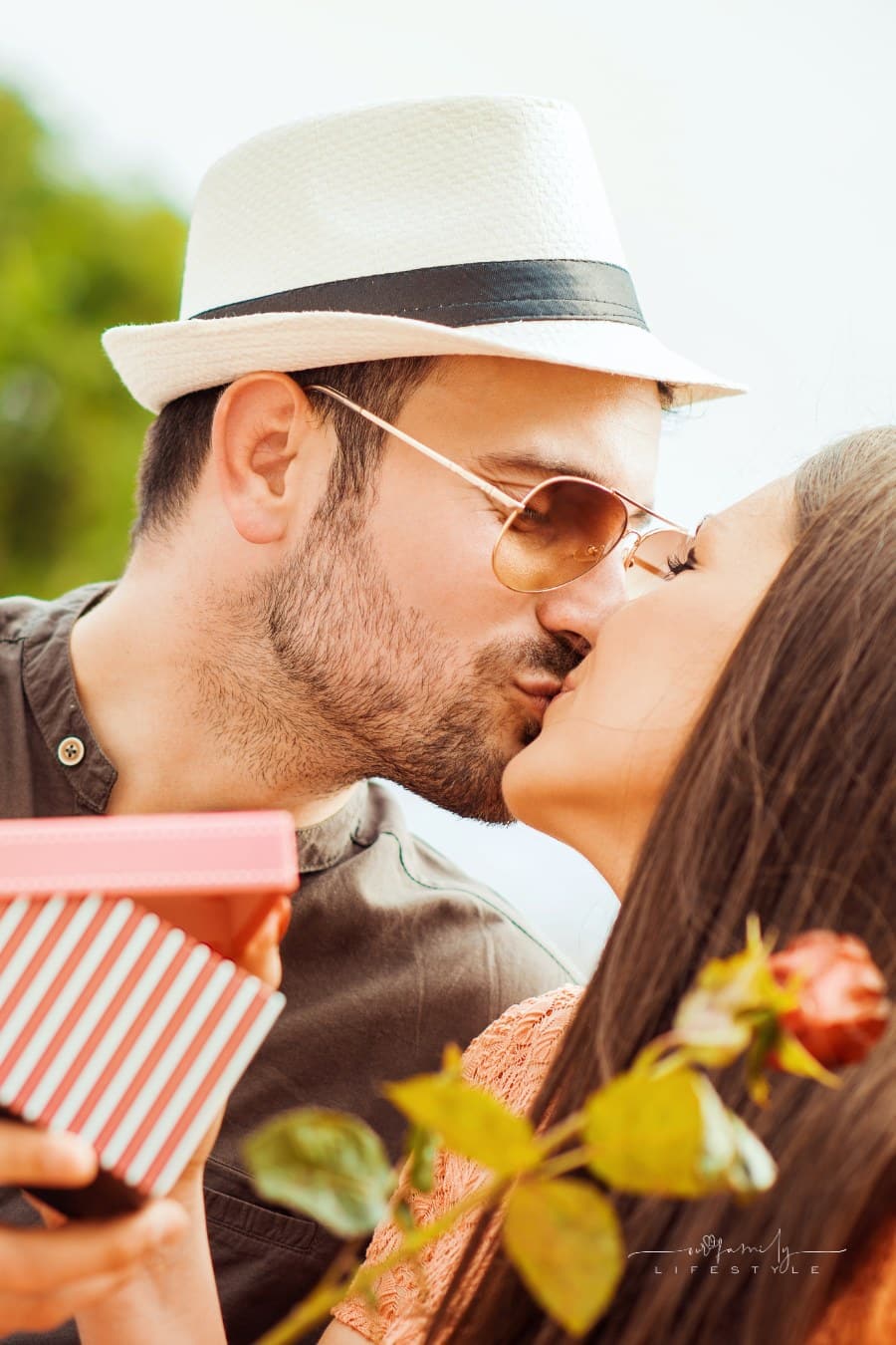 husband and wife kissing while holding a small gift box