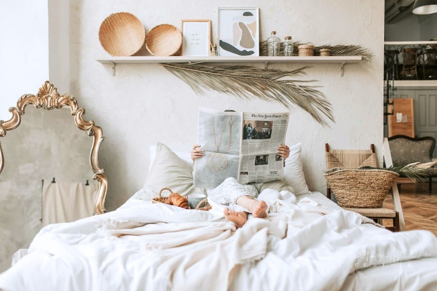 Photo of a Person Reading a Newspaper on the Bed