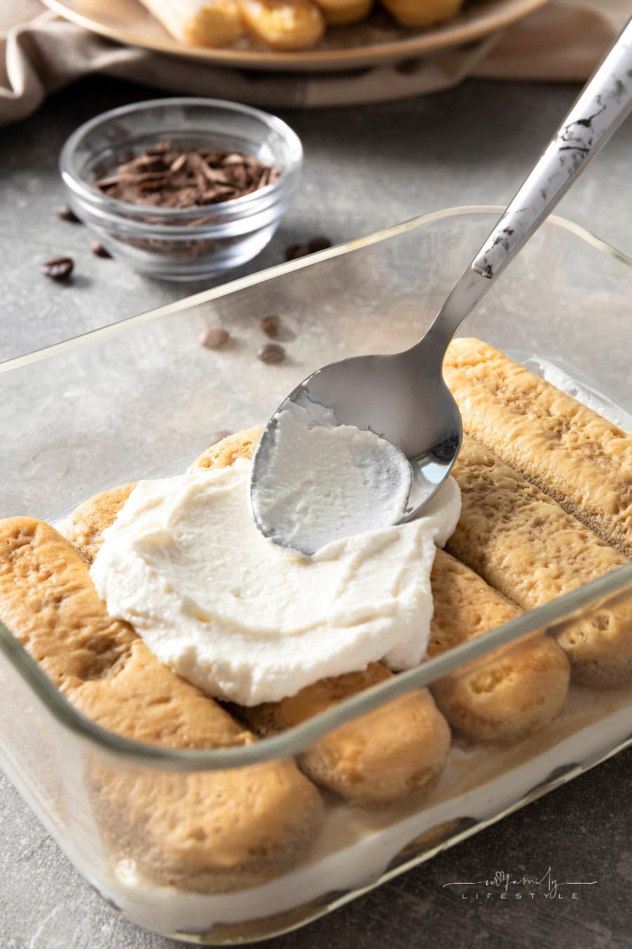 spoon spreading Zabaione Filling onto layer of ladyfingers for tiramisu