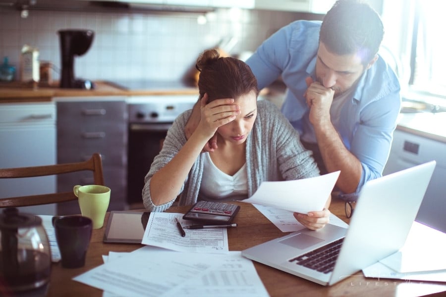 couple looking at bills over a laptop